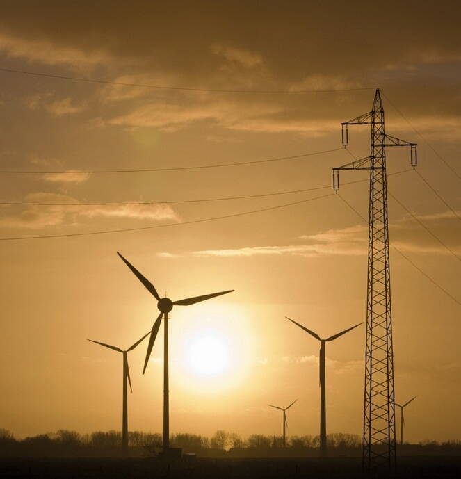 Strombeschaffung Windräder im Sonnenuntergang mit Stromleitung